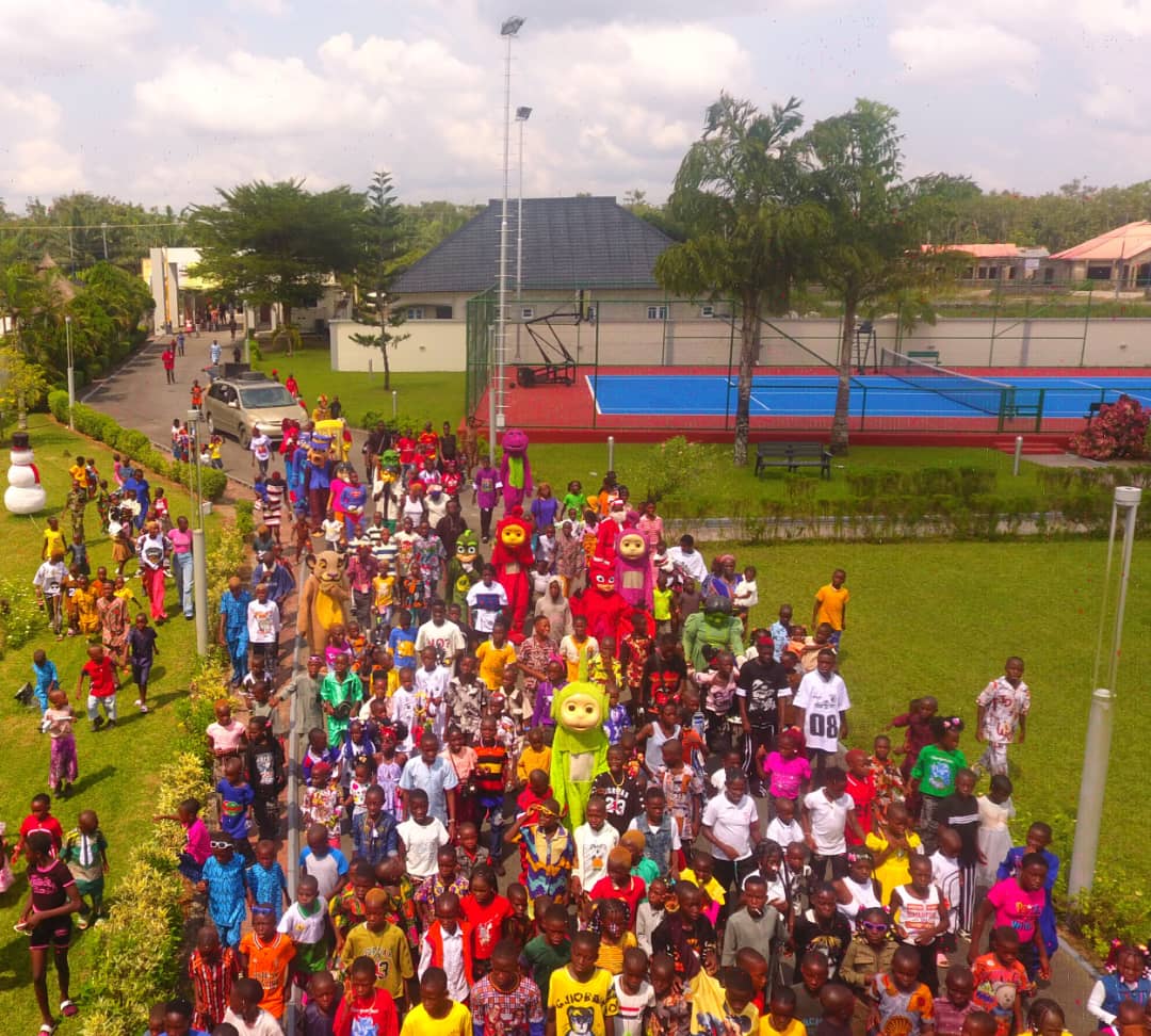 Aerial drone view — children marching with costumed characters across the venue grounds